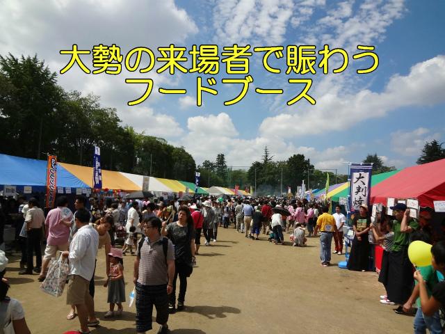 大勢の来場者で賑わうフードブース。沢山の人がいろんな屋台の前を買い物しながら行きかう様子