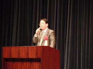 宮本初義会長が壇上に立ち講演している写真