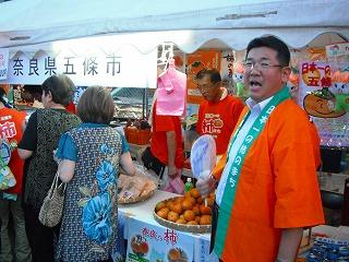 五條市のブースで市長が柿をアピールしている写真