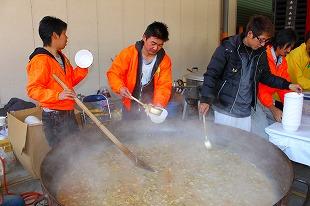 大きな鍋からお椀へ豚汁をよそう男性3人の写真