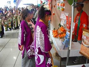 紫のハッピを着た女性2人が五條市のブースで柿を見ている写真