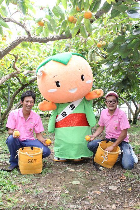 マスコットキャラクターの柿奈と並んで写真に写る若手柿生産者の写真