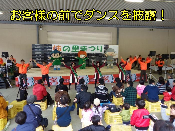 ゆるキャラゴーカスター達が舞台上で踊っていて部隊下では柿の里娘と生産者達が一緒に踊っている写真