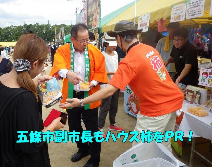 五條市副市長が柿の試食をお客様へ勧める写真