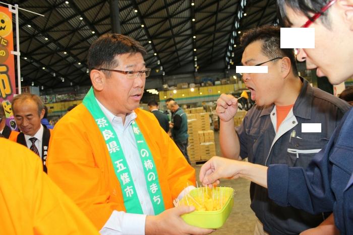 市長が柿の試食をすすめている写真