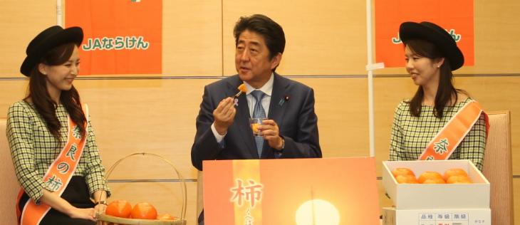 安倍総理が柿の里娘と並んで柿を試食している写真