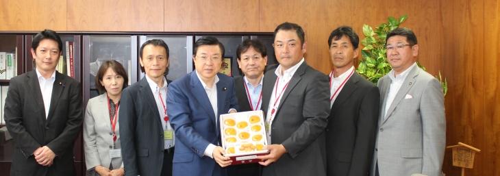 磯崎農林水産副大臣へハウス柿を贈呈している写真