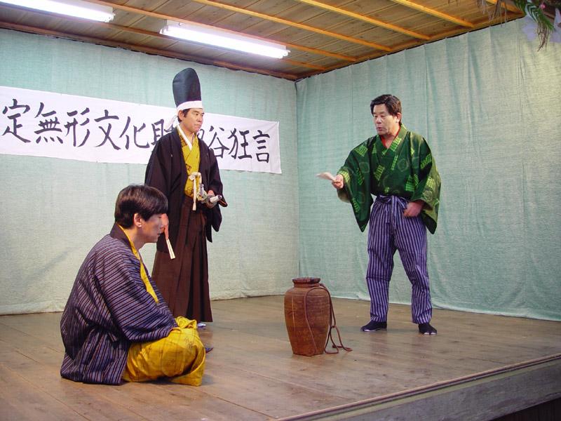 惣谷狂言を舞台で演じている3人の男性の写真