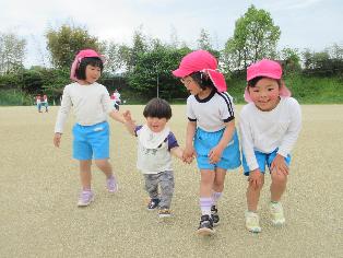 1歳児と5歳児が手をつないで歩いているところ