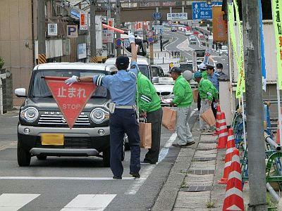 高越安全啓発活動にて警官が車を止めて活動のパンフレットを並んでいる車に配布している写真