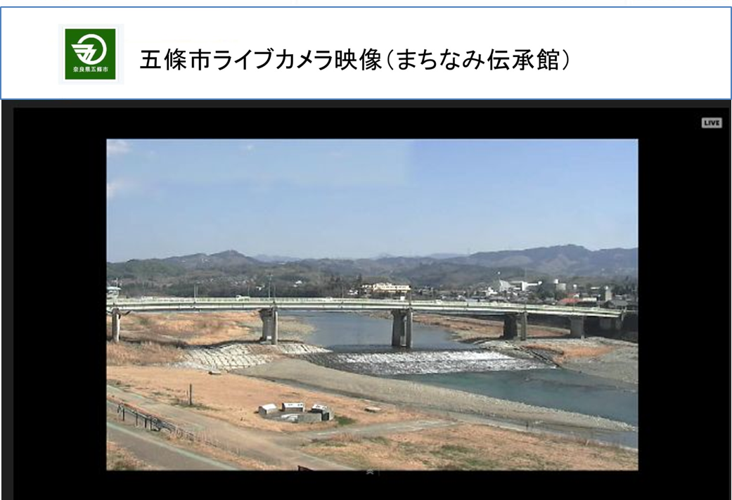 青空の下に橋がかかった小川や土手が写っている、ライブカメラのサンプル画像の写真